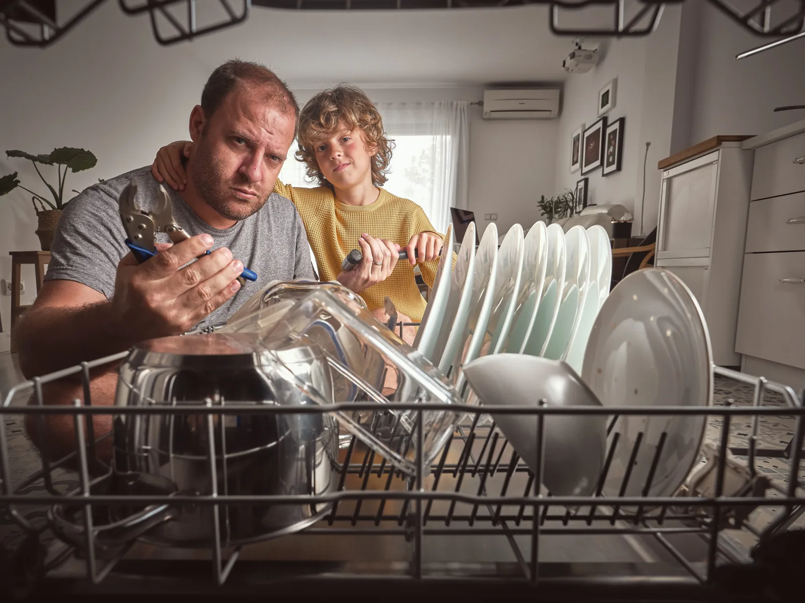 Father and young child loading the dishwasher together at home